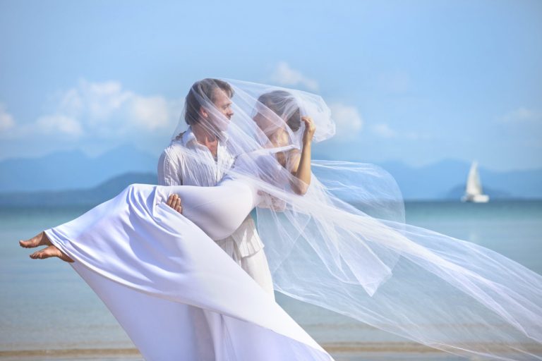 Brautpaar tanzt am Strand vor Blauem Himmel, romantische Athmosphäre